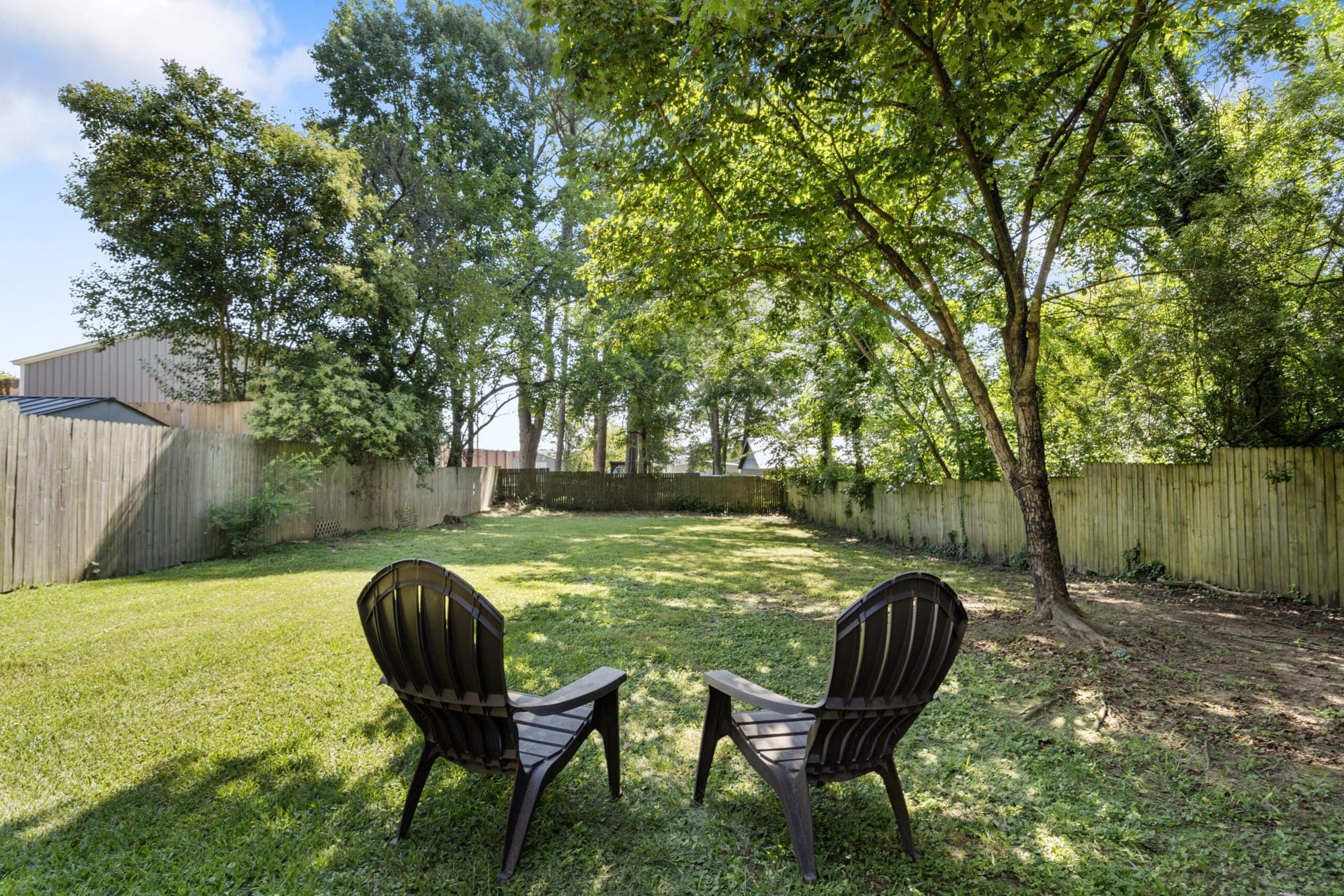Fenced backyard with two Adirondack chairs