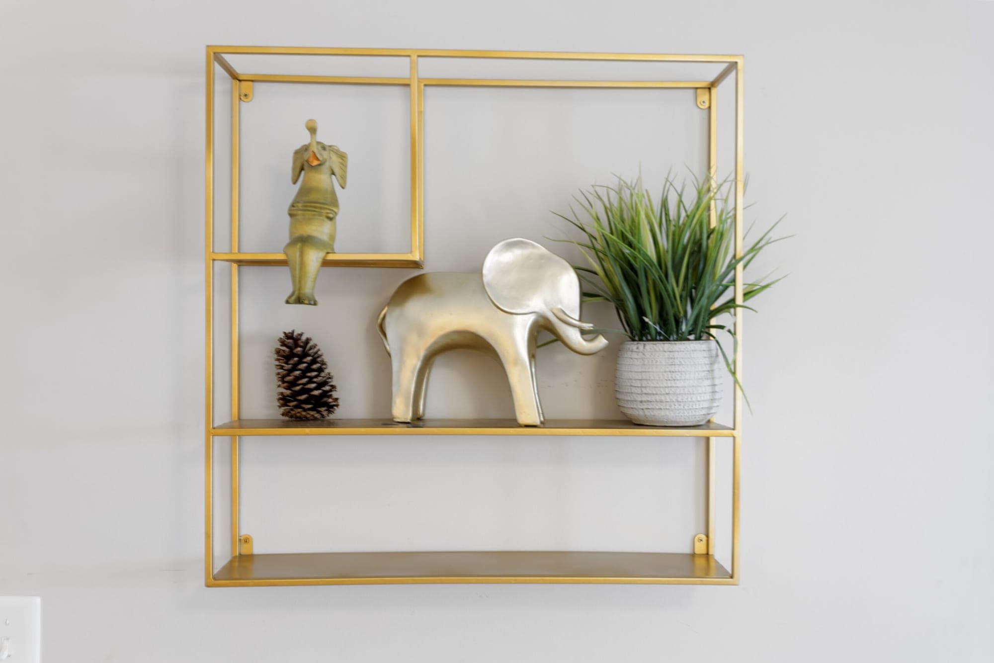 Gold wall shelf with a brass elephant and plant