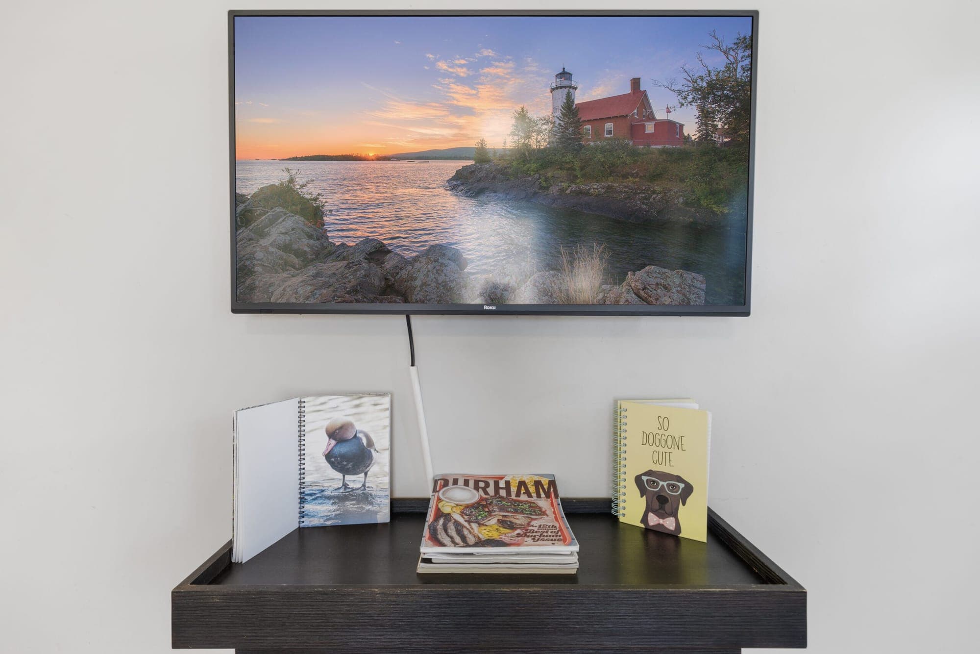 Wall-mounted TV above a console with books