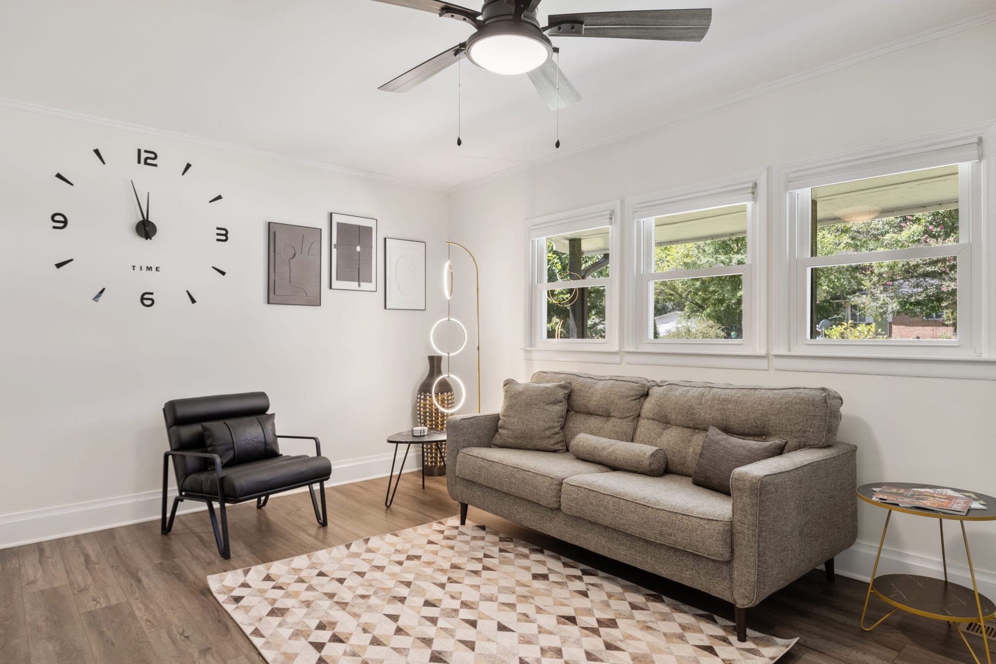 Living room with a gray sofa, black armchair and wall clock