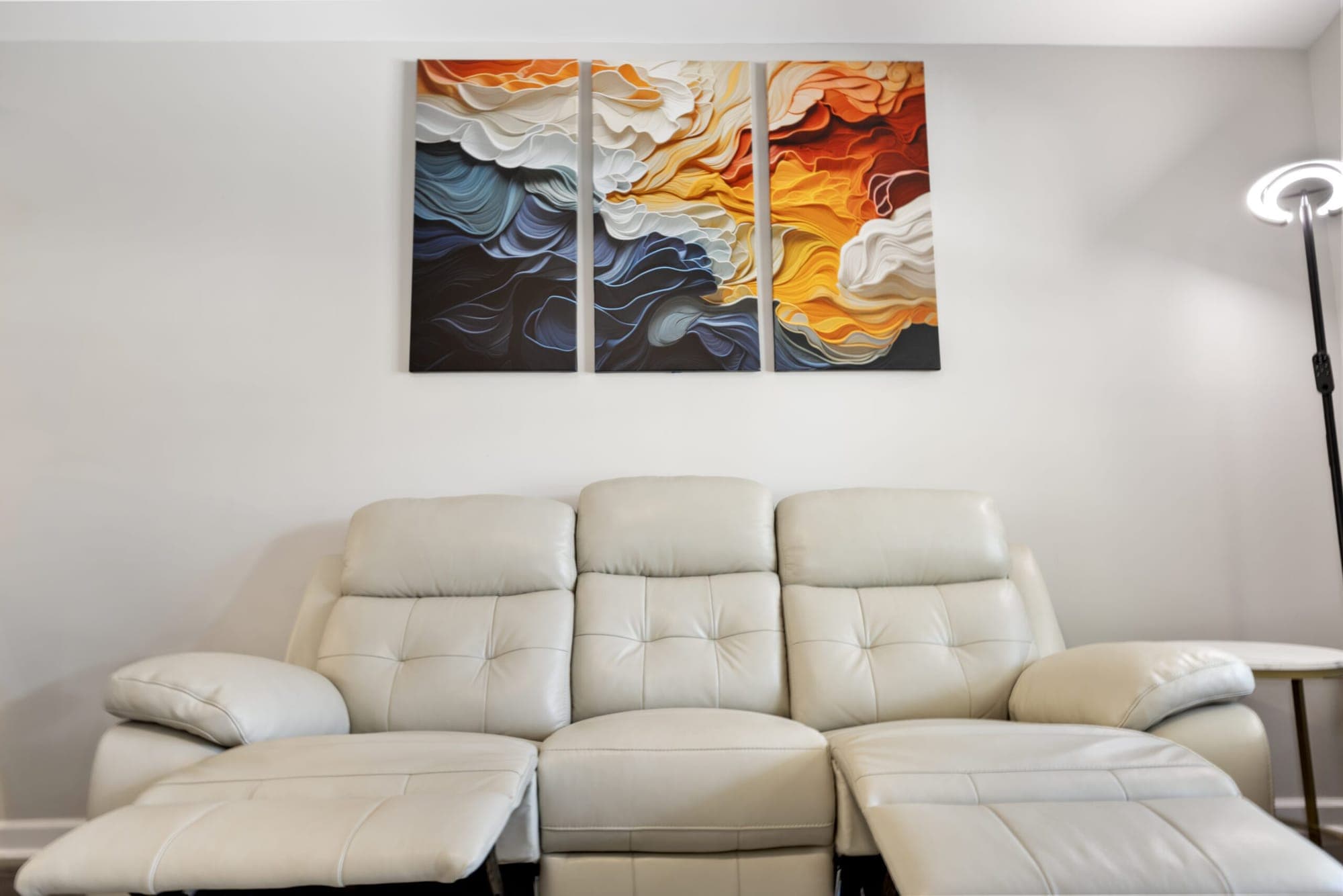 Cream reclining sofa under abstract wall art
